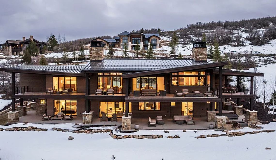 Rear elevation of 9406 N. Uinta Drive lit at dusk in snow