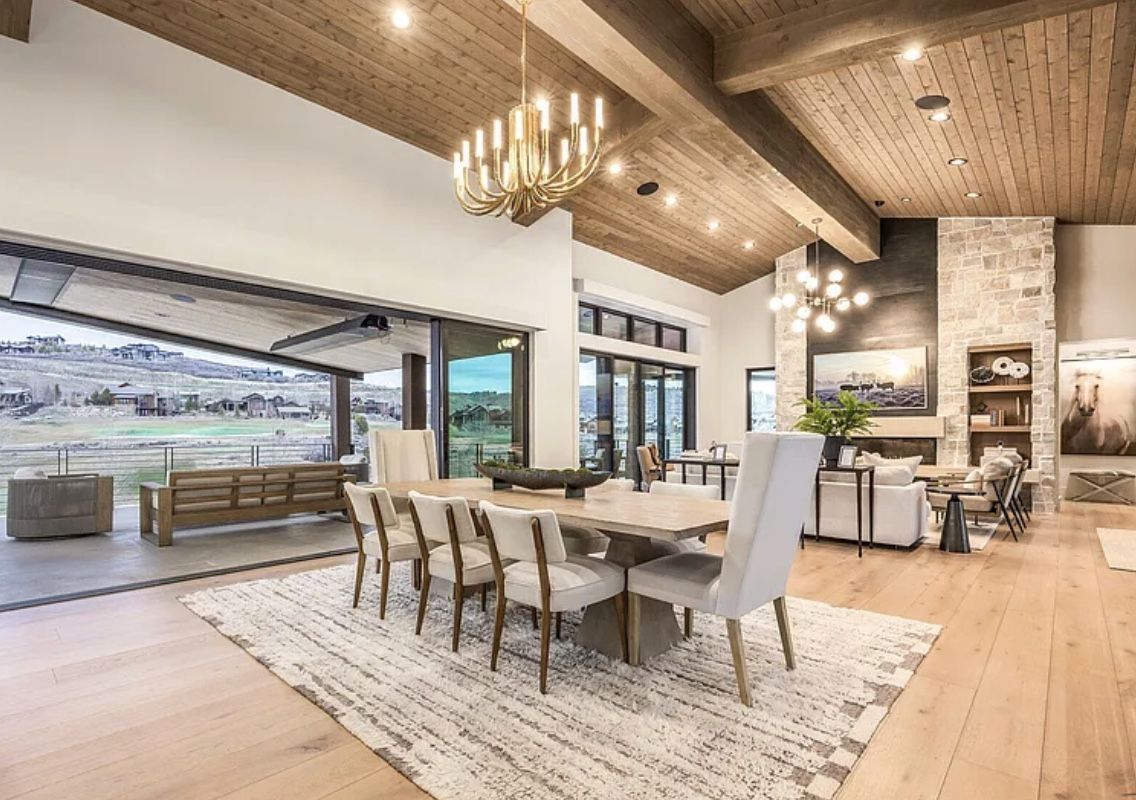 Dining room under timber beams opening to a covered terrace